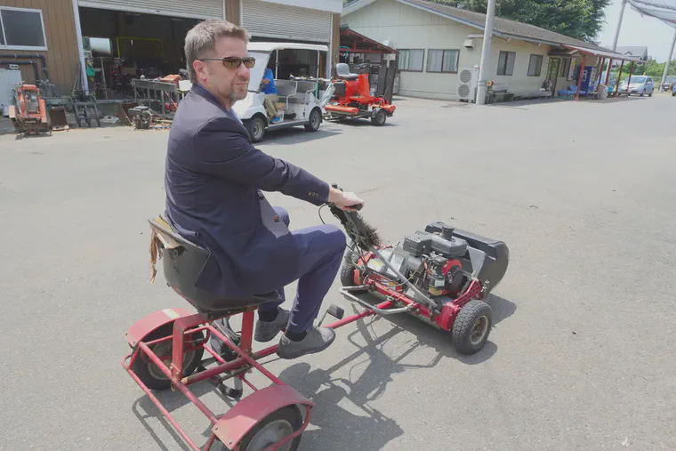 Riding a classic greens mower sulky in the maintenance yard.